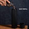 The HexClad matte black adjustable pepper mill demonstrating its ten distinct grind settings on a kitchen counter.