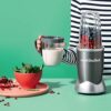 A fresh nutritious smoothie in a 24-ounce Nutribullet cup next to the dark gray personal smoothie blender unit.