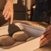 An expert baker using the Ooni easy-lift dough spatula to manage pizza dough during preparation.