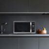 A Farberware 1.1 cu ft countertop microwave being used in a home kitchen to reheat a dinner plate.