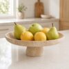 A handcrafted 10-inch Cotivaye travertine fruit bowl sitting on a modern kitchen countertop.