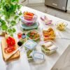 A collection of crystal-clear glass food storage containers organized neatly in a pantry shelf.