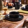 Full set of matte black stoneware dinnerware including dinner plates, salad plates, and cereal bowls.
