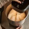 A baker using the Ooni Halo Pro spiral dough mixer to knead artisanal pizza dough in a home kitchen setting.