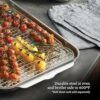 Stainless steel half sheet pan placed inside a home kitchen oven for roasting