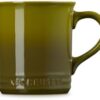 Lifestyle shot of the Olive Le Creuset stoneware mug set on a kitchen table for modern home dining.