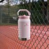 User holding the 64 oz insulated water jug by the handle during an outdoor activity.