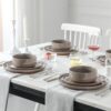 Side profile of the brown stoneware plates stacked to display the refined, pottery-inspired craftsmanship.