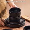 Microwave and dishwasher safe Famiware matte black stoneware arranged on a dining table.