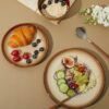 A stylish stack of rustic ceramic plates and bowls from the Pokini 12-piece set.